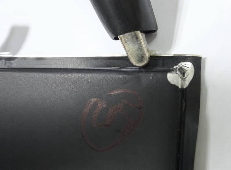Lithium-ion pouch cell tab sealing defect showing electrolyte leakage and aluminum tab corrosion caused by improper CPP tab sealant coverage and incorrect top seal dimensions.