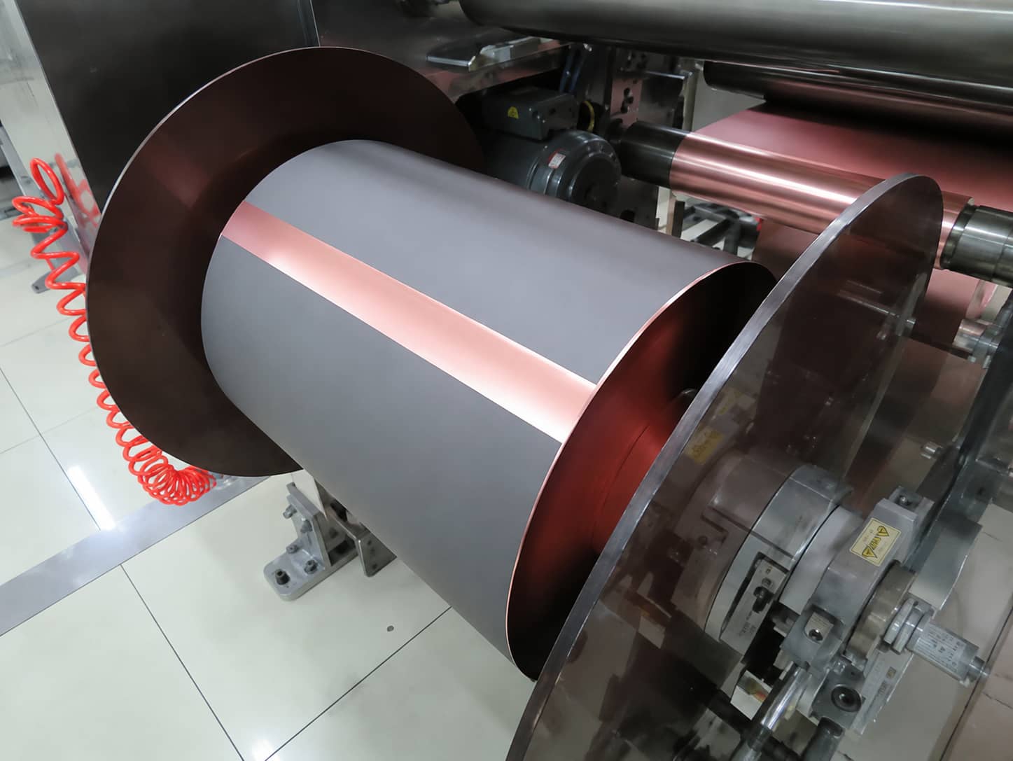 Roll-to-roll electrode coating machine for lithium-ion batteries, including slurry feeding system, coating head control zone and multi-stage drying oven.