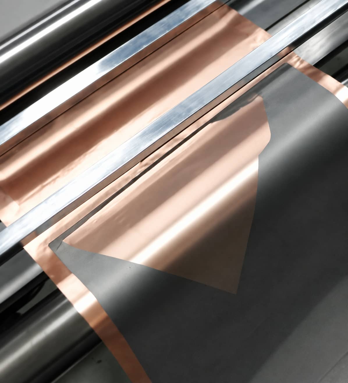 Lithium-ion battery electrode coating partially delaminating from copper foil during novel binder pilot-line processing, showing an adhesion-related scale-up defect.